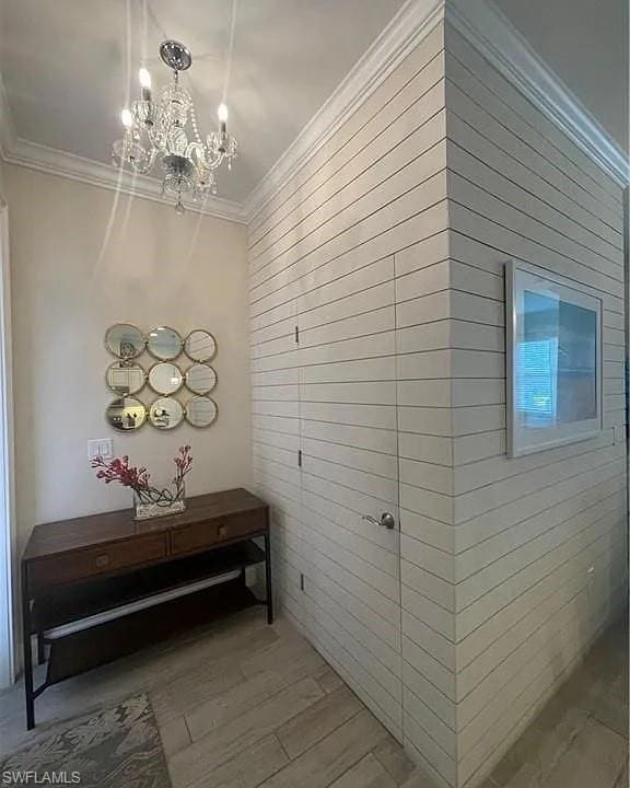 Hallway with a chandelier, ornamental molding, wood finished floors, and wooden walls