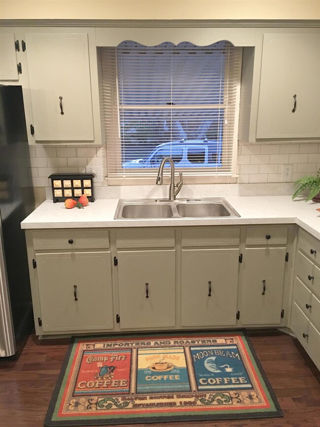 Double bowl stainless sink overlooks covered patio/carport, features pull-down faucet and task lighting hidden above. 