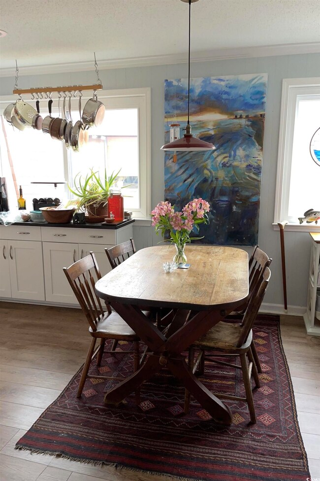 Dining space featuring light wood-style flooring, crown molding, and a textured ceiling
