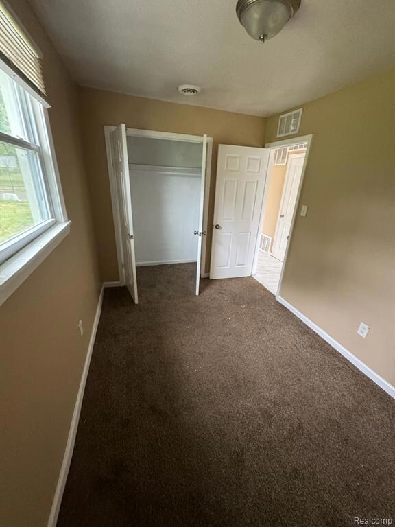 Unfurnished bedroom with dark colored carpet and a closet