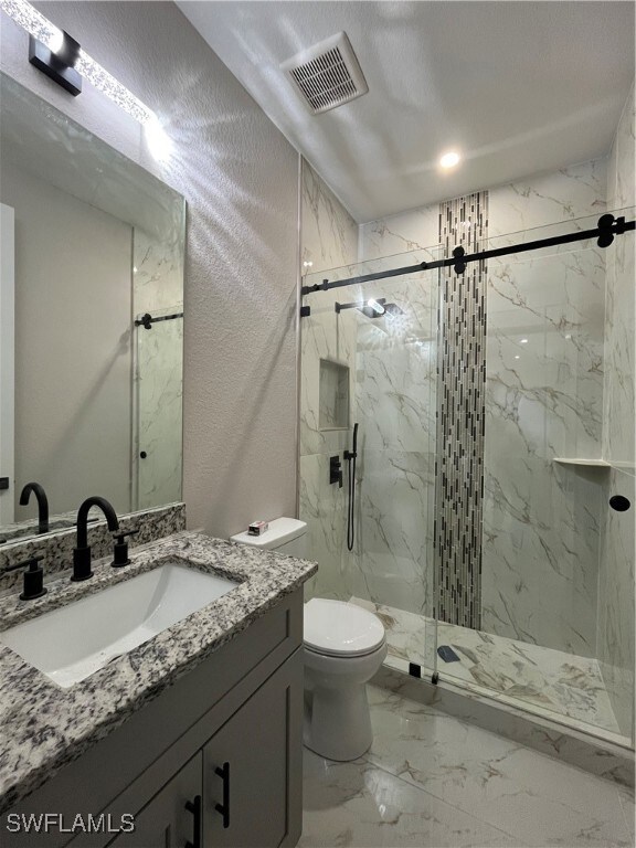 Bathroom with vanity, toilet, and an enclosed show
