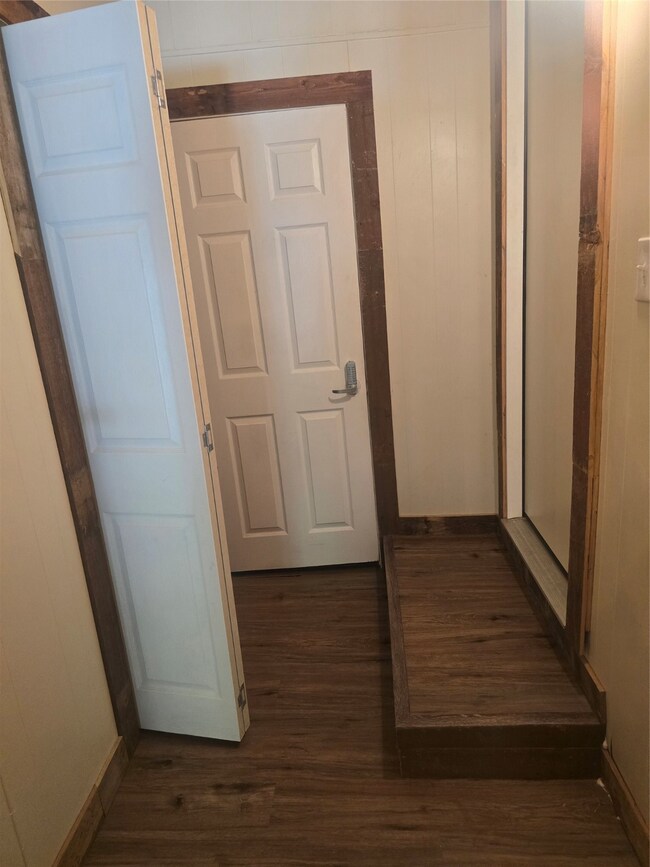 Hall with dark wood-type flooring and wood walls