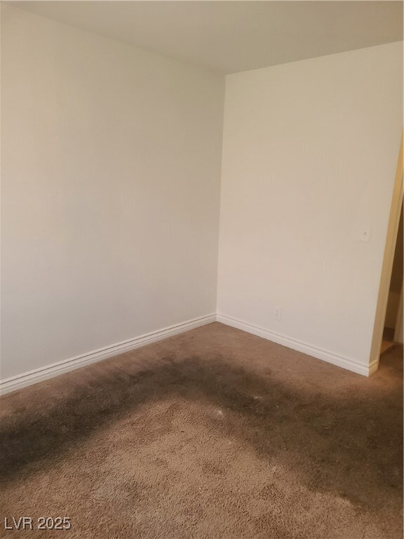 Unfurnished room with dark carpet and baseboards
