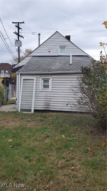 View of property exterior featuring a lawn, roof with shingles, and a chimney
