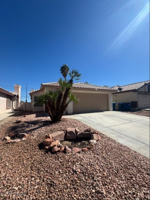 Single story home with concrete driveway, a tile roof, stucco siding, and an attached garage