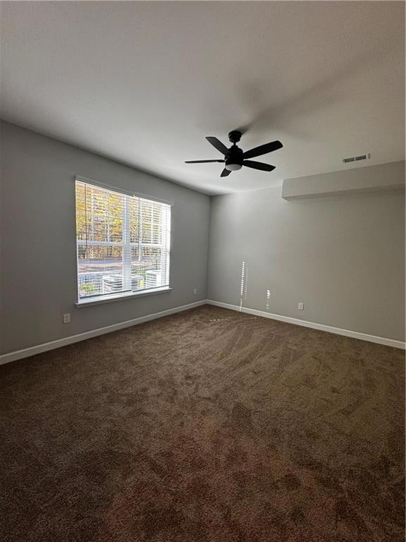 Empty room with dark carpet and ceiling fan