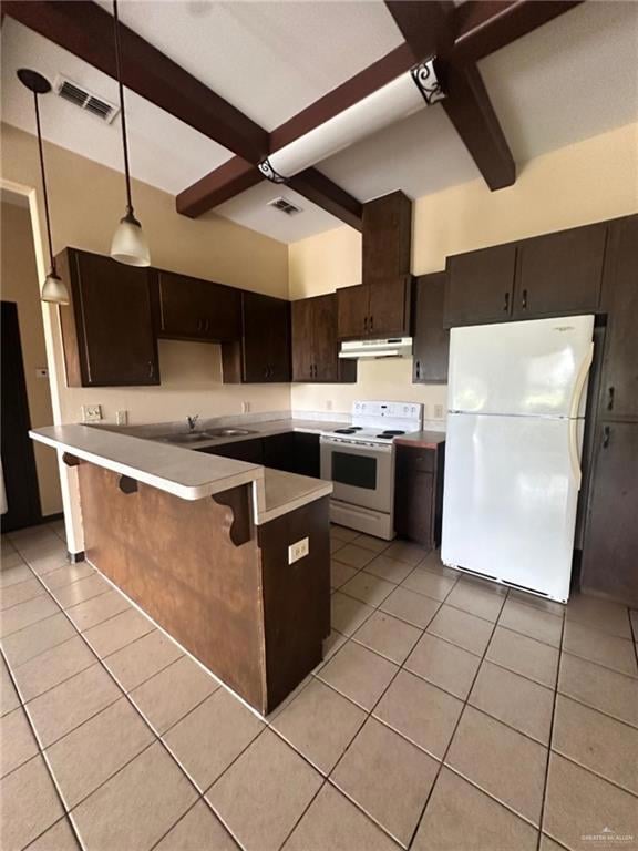 Kitchen with white appliances, under cabinet range hood, beam ceiling, light tile patterned floors, and a peninsula