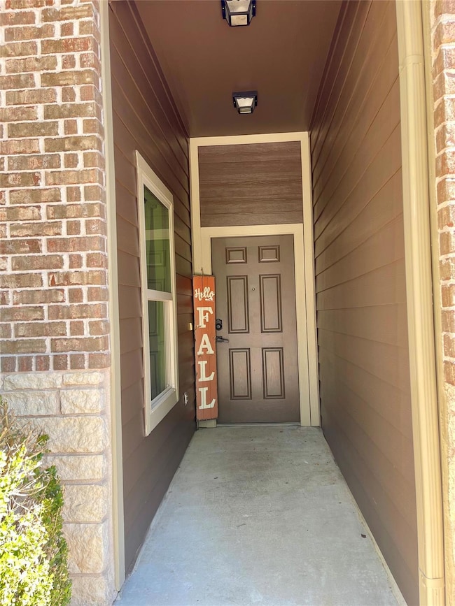 Entrance to property with covered porch and brick