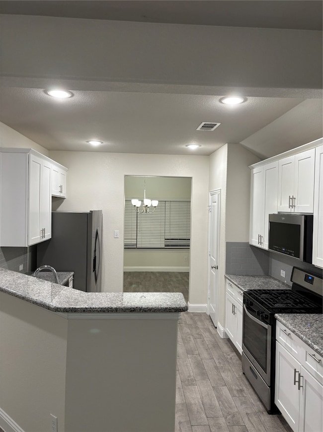 Kitchen featuring range, light stone counters, white cabinets, light wood-style floors, and fridge