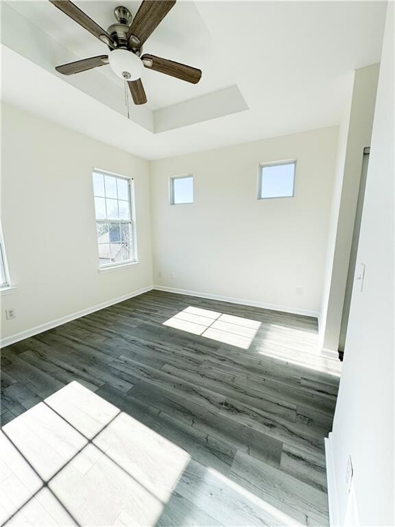 Unfurnished room featuring ceiling fan, dark hardw