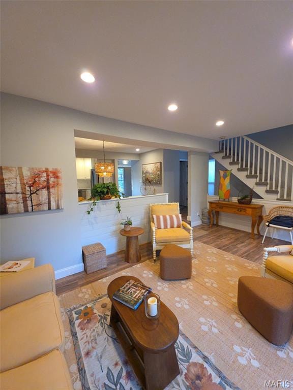 Living room with wood finished floors, recessed lighting, and stairway