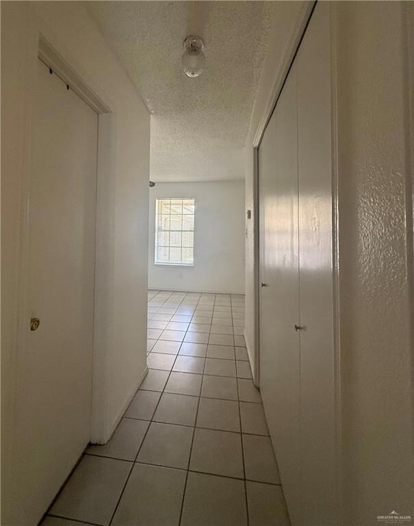 Corridor featuring a textured ceiling and light tile patterned floors