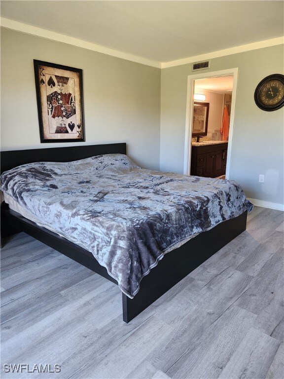 Bedroom with light wood-style floors and ensuite bath