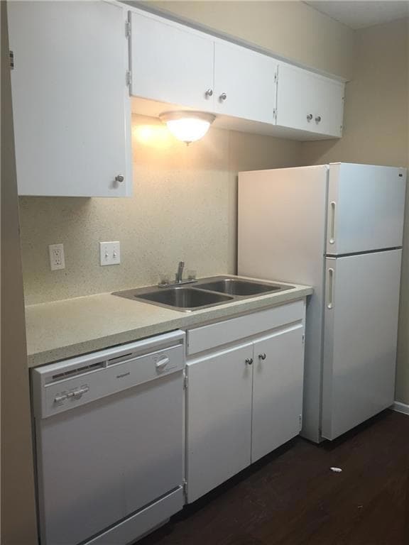 Kitchen featuring white appliances, light countertops, white cabinetry, and dark wood finished floors