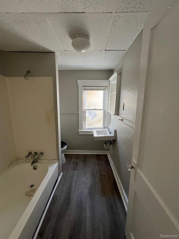 Bathroom with dark wood-type flooring, shower / bathtub combination, and a drop ceiling