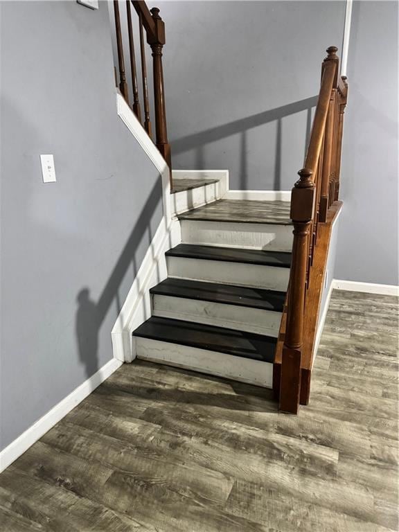 Staircase with wood finished floors and baseboards