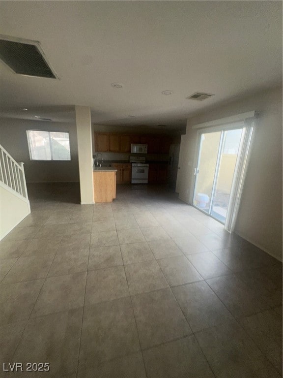 Unfurnished living room with stairway and light tile patterned floors