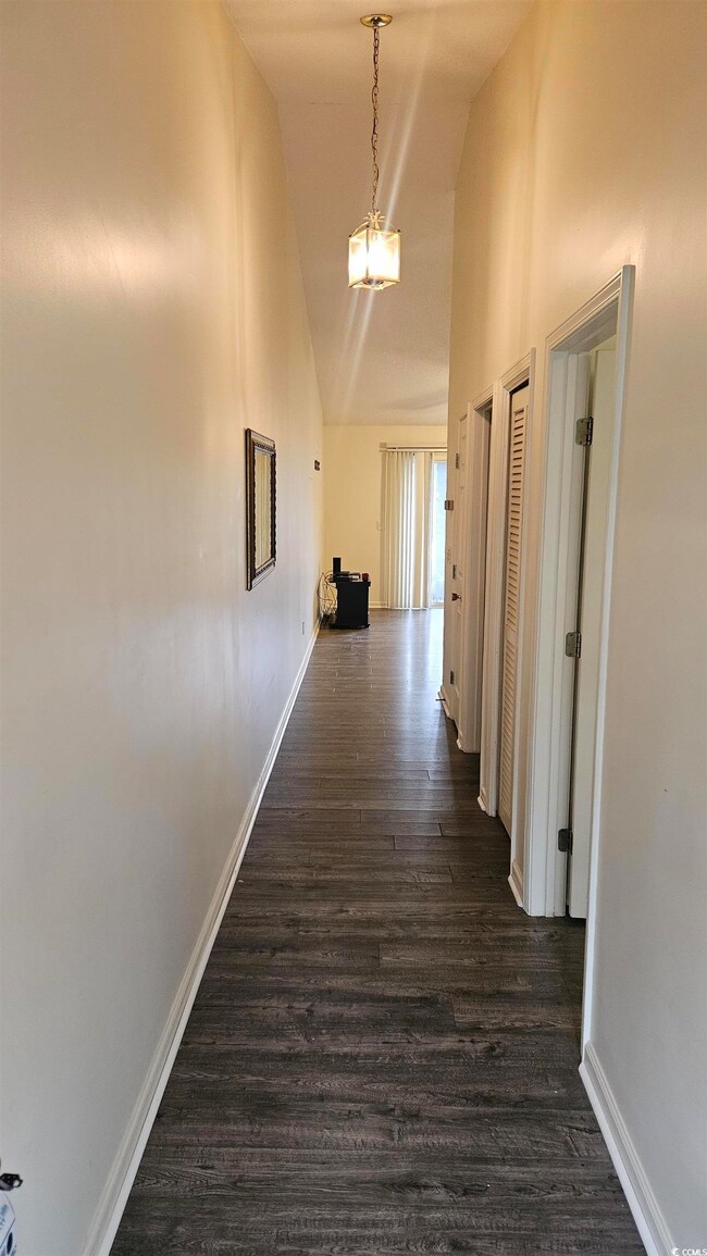 Hallway featuring a chandelier, dark hardwood / wo