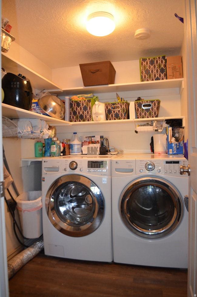 Washroom with a textured ceiling, dark wood finished floors, and independent washer and dryer