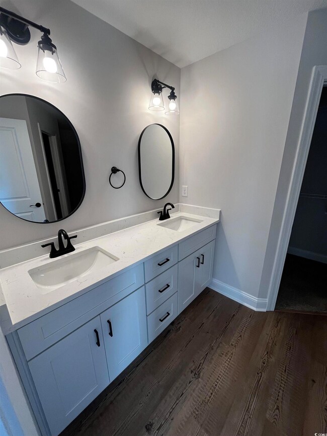 Bathroom featuring baseboards, double vanity, a si