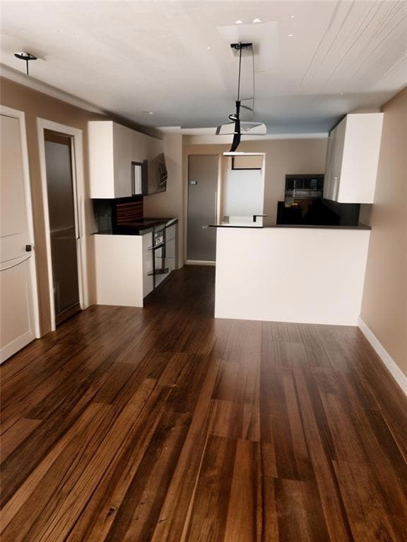 Kitchen featuring white cabinetry, dark wood finished floors, dark countertops, a peninsula, and modern cabinets
