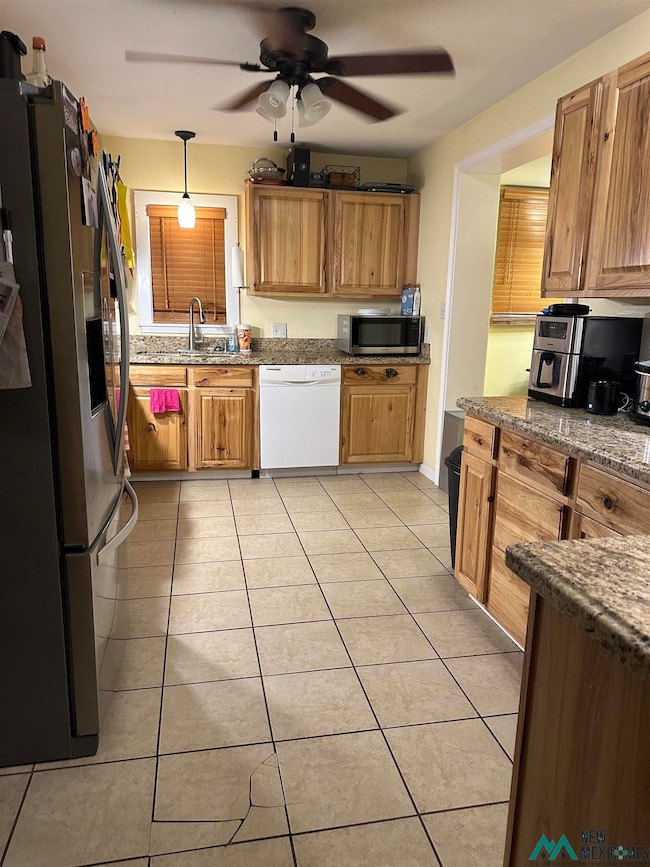 Kitchen featuring appliances with stainless steel finishes, ceiling fan, light tile patterned floors, pendant lighting, and dark stone counters
