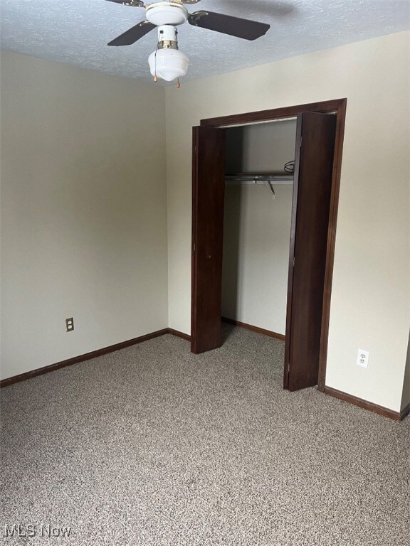 Unfurnished bedroom featuring carpet, a closet, a textured ceiling, and ceiling fan