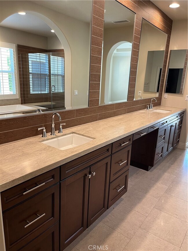 Primary bathroom with dual sinks, rich cabinetry and large closet with built ins