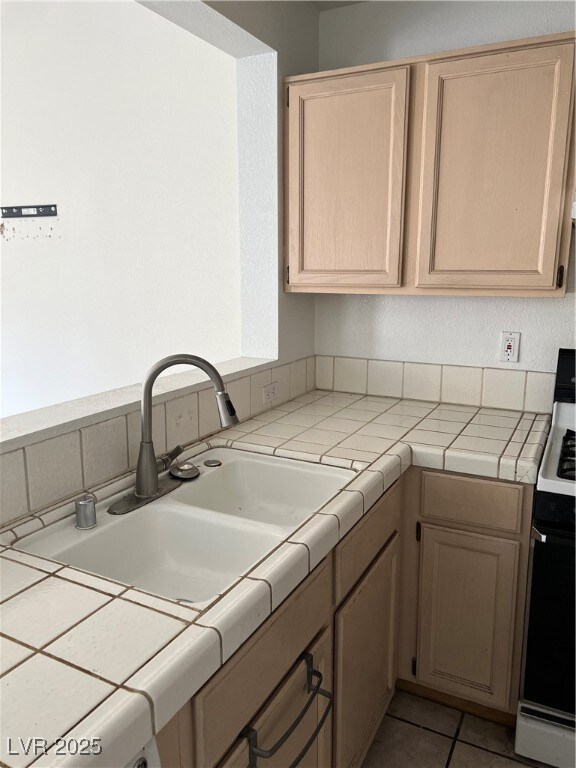 Kitchen featuring a sink, tile counters, range, an