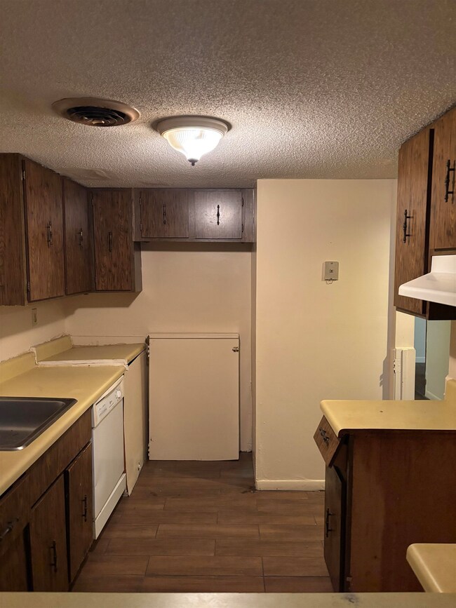 Kitchen with white dishwasher, dark wood-type floo