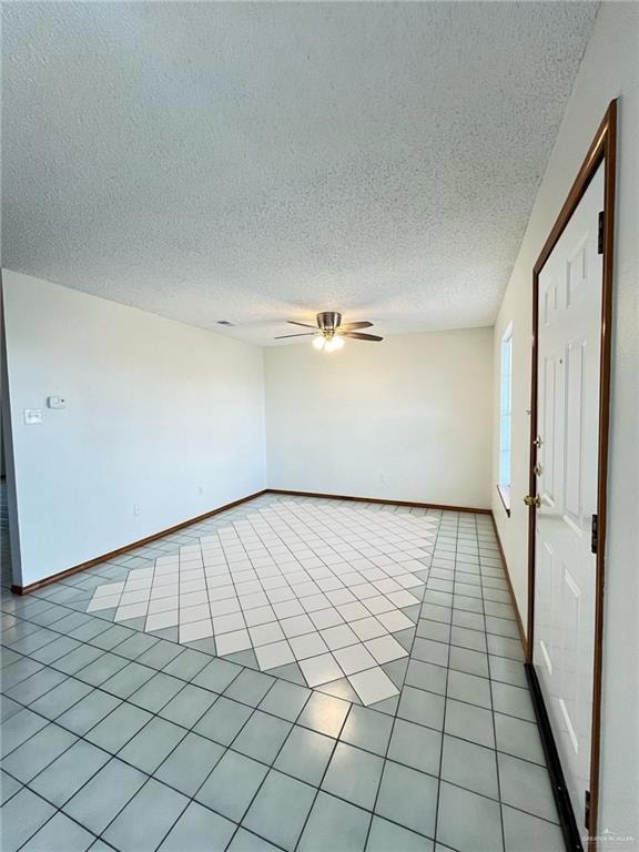 Spare room featuring a ceiling fan, light tile patterned floors, and a textured ceiling