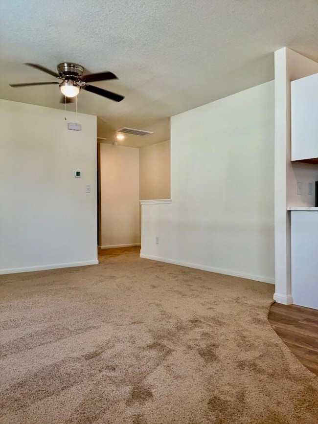 Spare room with a textured ceiling, light carpet,