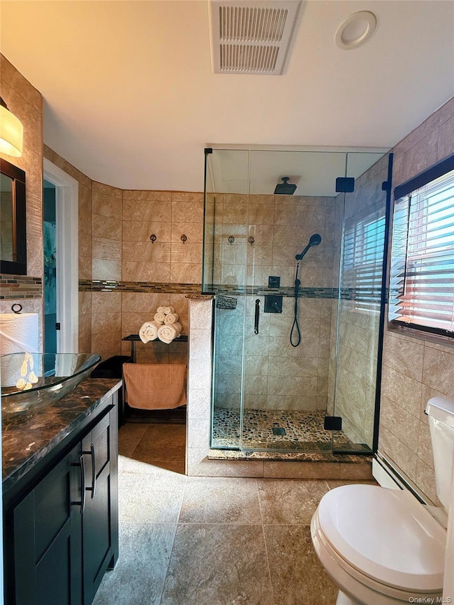 Bathroom with tile walls, vanity, a stall shower, and tile patterned floors