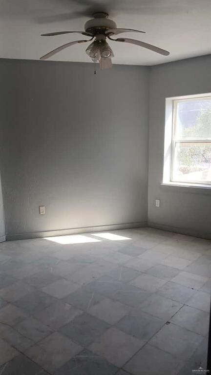 Spare room with ceiling fan and baseboards