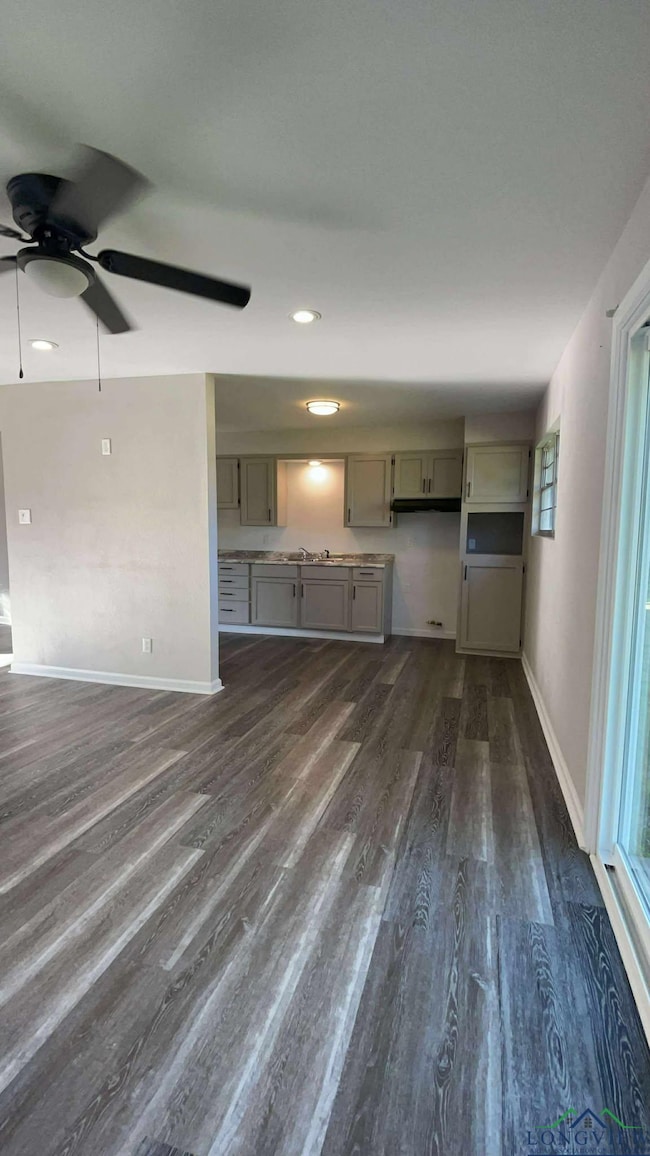 Unfurnished living room with dark wood-style floors, a ceiling fan, baseboards, healthy amount of natural light, and recessed lighting