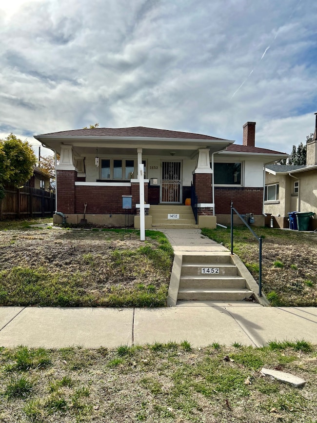 View of front of property featuring covered porch, brick siding, and a chimney