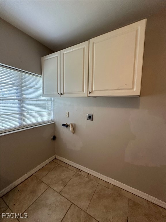 Laundry room with hookup for an electric dryer, light tile patterned floors, cabinet space, and washer hookup