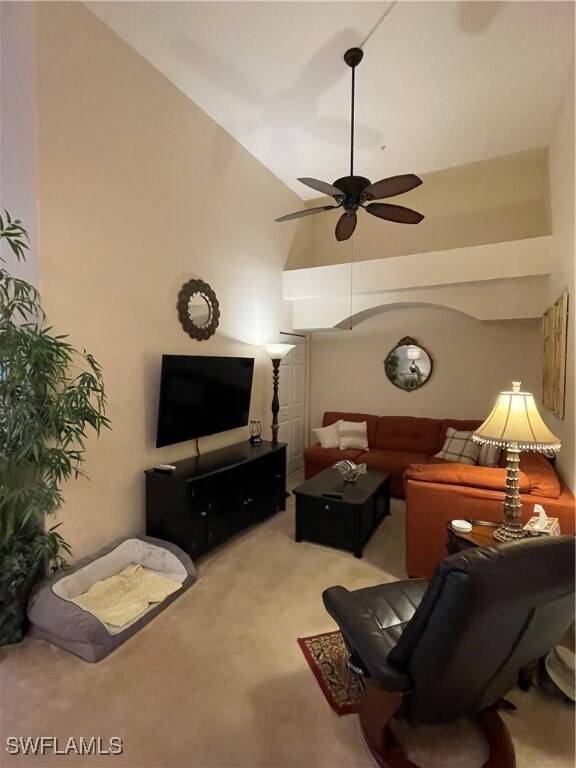 Den with light carpet, high vaulted ceiling, and c