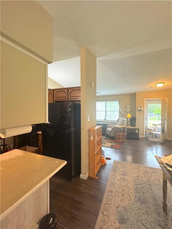 Kitchen featuring freestanding refrigerator, a textured ceiling, healthy amount of natural light, dark wood-style floors, and open floor plan