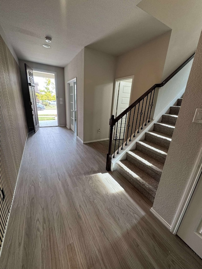 Foyer with a textured ceiling, stairs, and wood finished floors