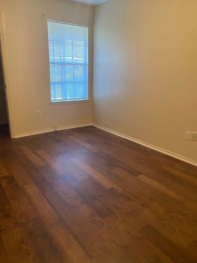 Empty room with dark wood-style flooring and base