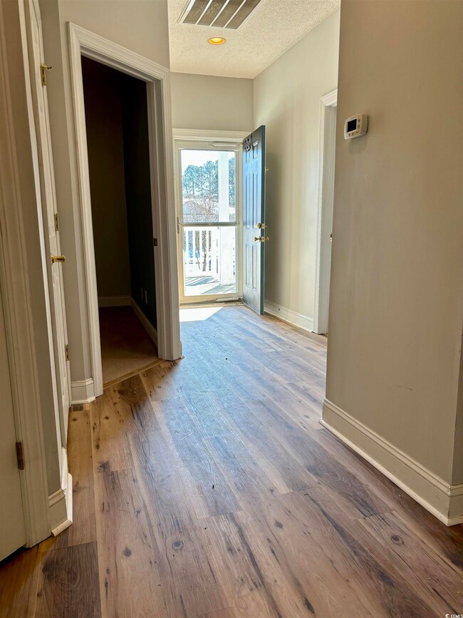 Interior space featuring visible vents, baseboards, a textured ceiling, and wood finished floors