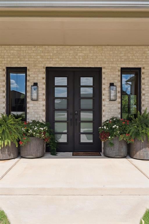 View of exterior entry featuring brick siding and french doors