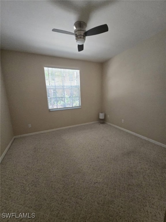 Carpeted spare room with a ceiling fan and baseboa
