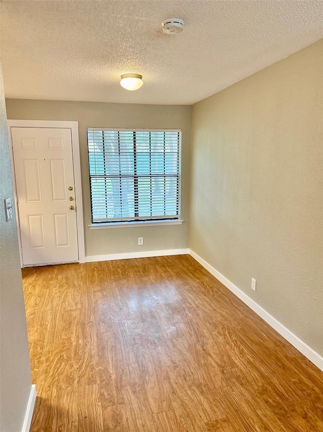 Foyer with baseboards, a textured ceiling, and wo