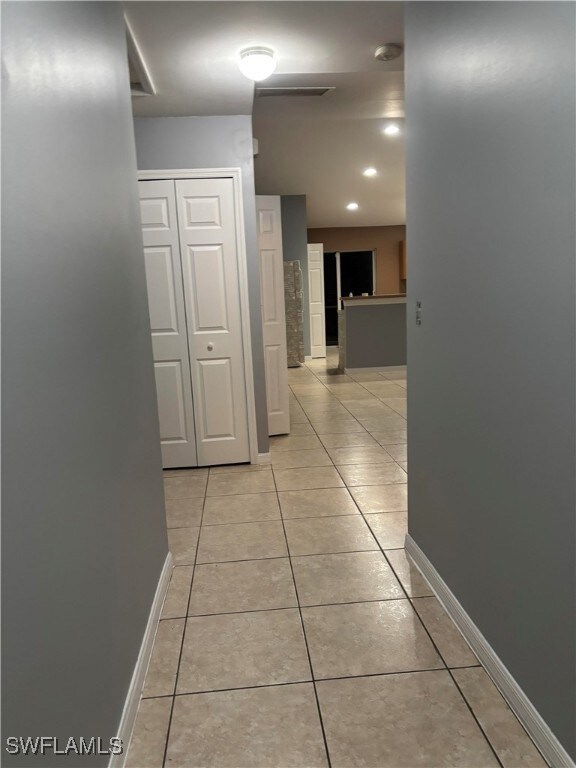 Hall with light tile patterned floors and baseboar