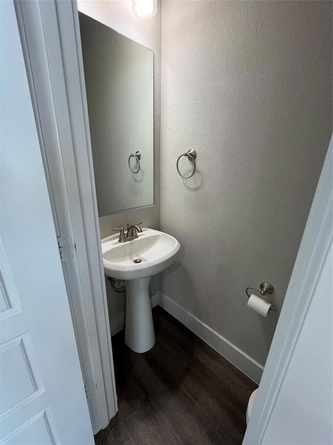 Bathroom featuring a sink, a textured wall, basebo