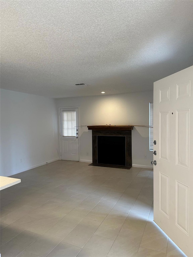 Unfurnished living room featuring a textured ceil