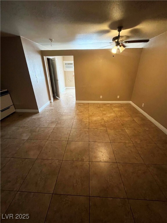 Unfurnished room featuring a ceiling fan, a wall m