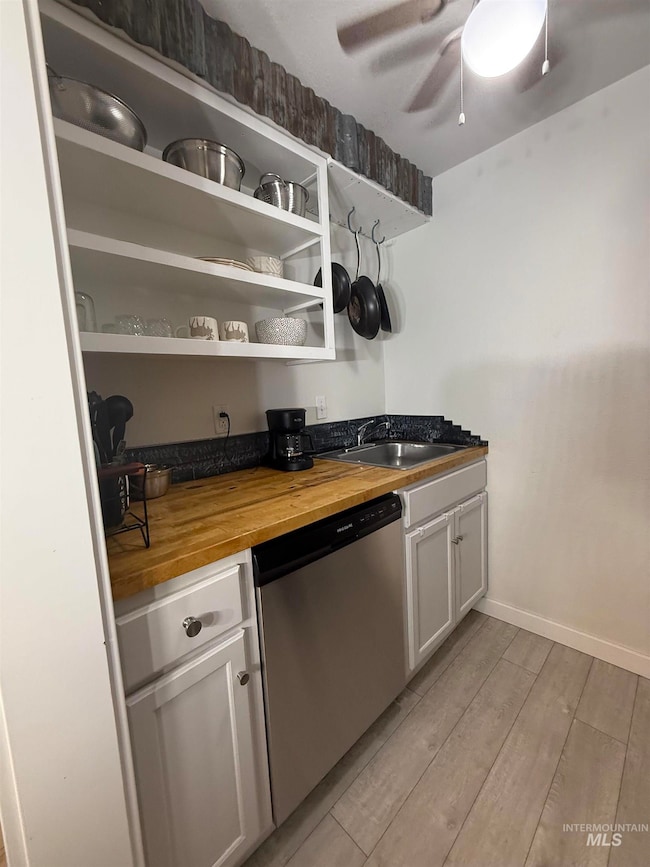 Kitchen featuring dishwasher, wooden counters, light wood-style floors, white cabinetry, and ceiling fan